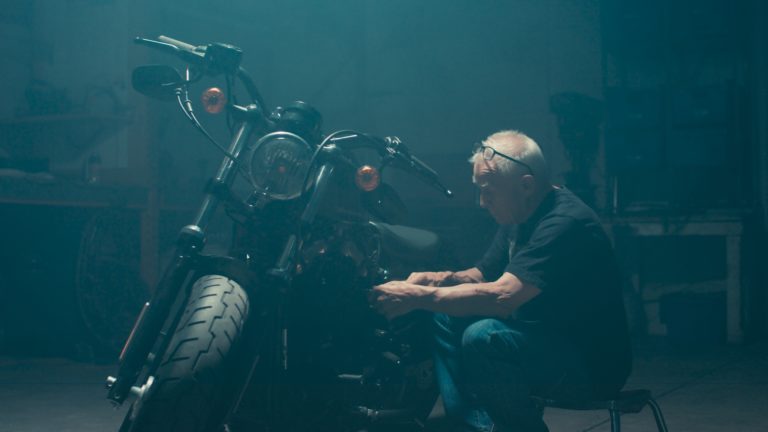 gray haired man fixing motorbike