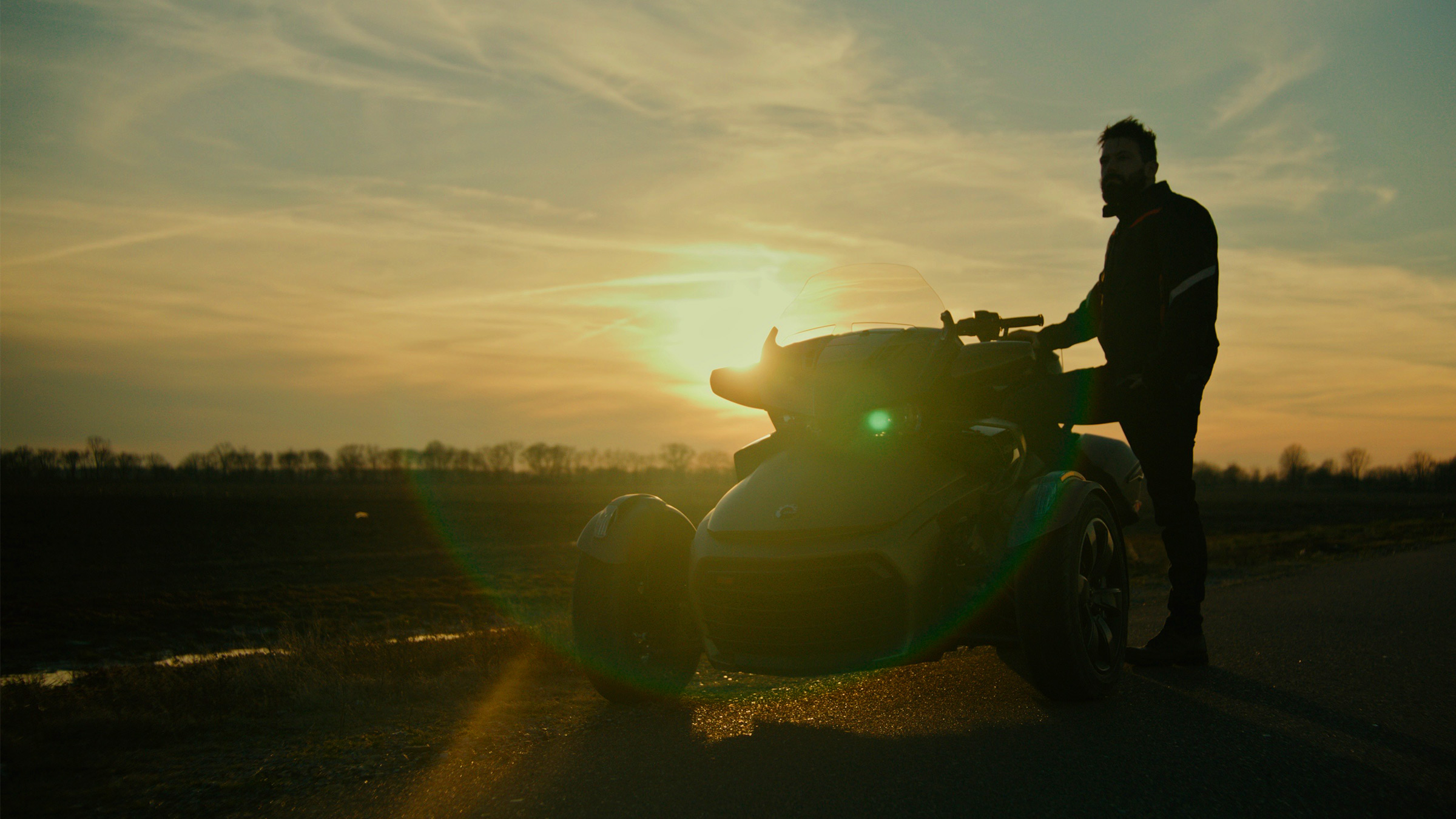 Man leaning against motortrike against the sunset