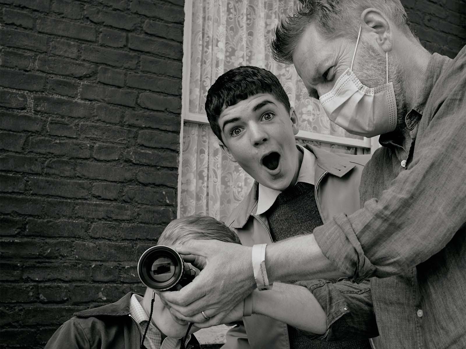 Kenneth Branagh shares a joyful moment with Jude Hill (Buddy), and Lewis McAskie (Will) on location for Belfast. 