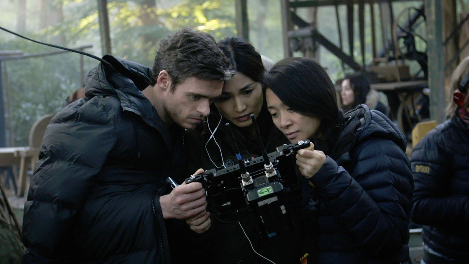 Richard Madden, Gemma Chan, and Chloé Zhao crowd around the monitor.