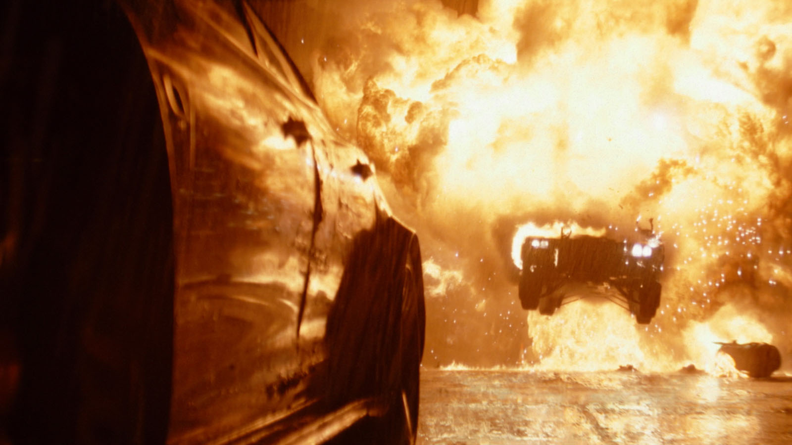 The Batmobile emerges from the fire behind Penguin’s fleeing vehicle. Image © Warner Bros.