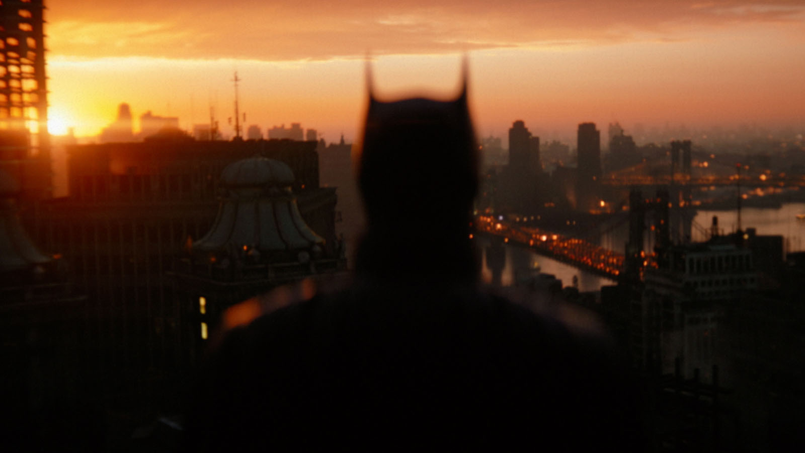 Batman looks out across the buildings and bridges of Gotham City. Image © Warner Bros.