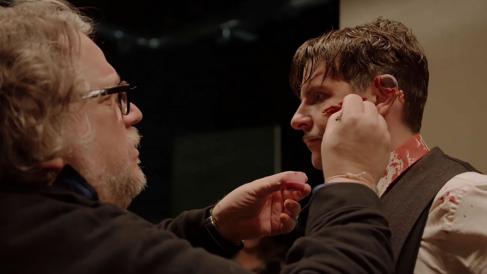 Guillermo del Toro takes a hands-on approach to Bradley Cooper’s makeup in Nightmare Alley. Image © Searchlight Pictures